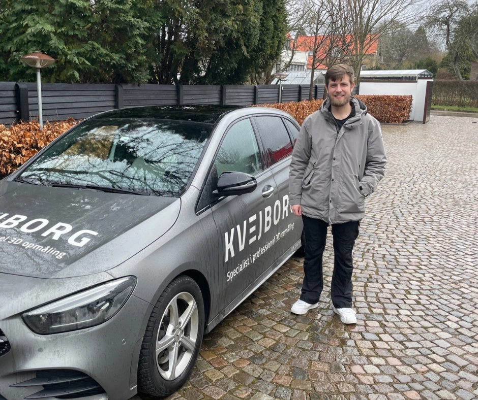 Mand ved siden af bil med KVEJBORG logo.