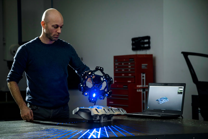 Mand scanner bildele med 3D-scanner og bærbar computer.