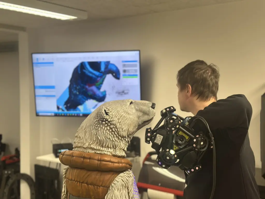 Mand bruger avanceret 3D-scanner ved siden af skærm.