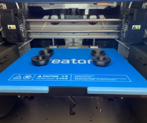 3D-printer med sorte plastikemner på trykplade.
